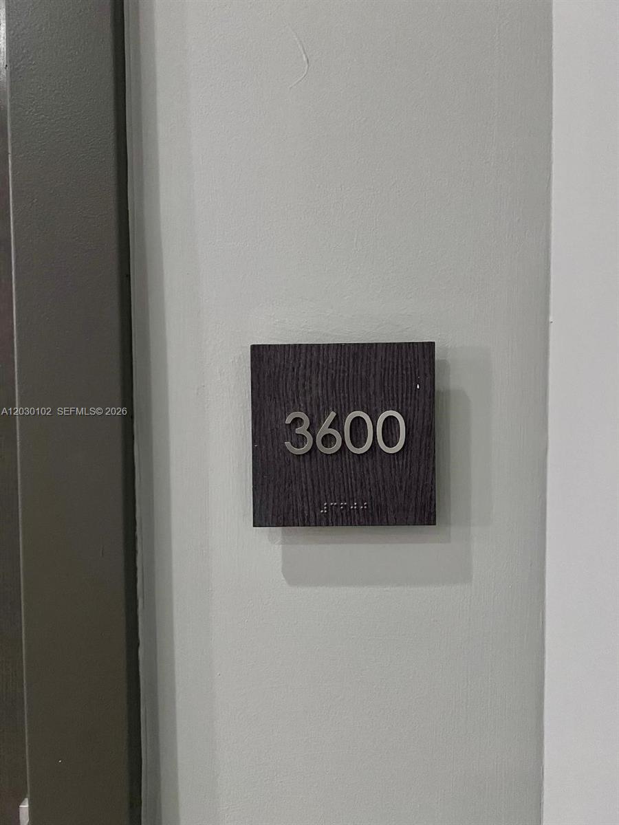 A dark wood square sign with the number 3600 is mounted on a gray wall — 1080 Brickell Ave # 3600, Miami FL 33131, MIAMI, FL