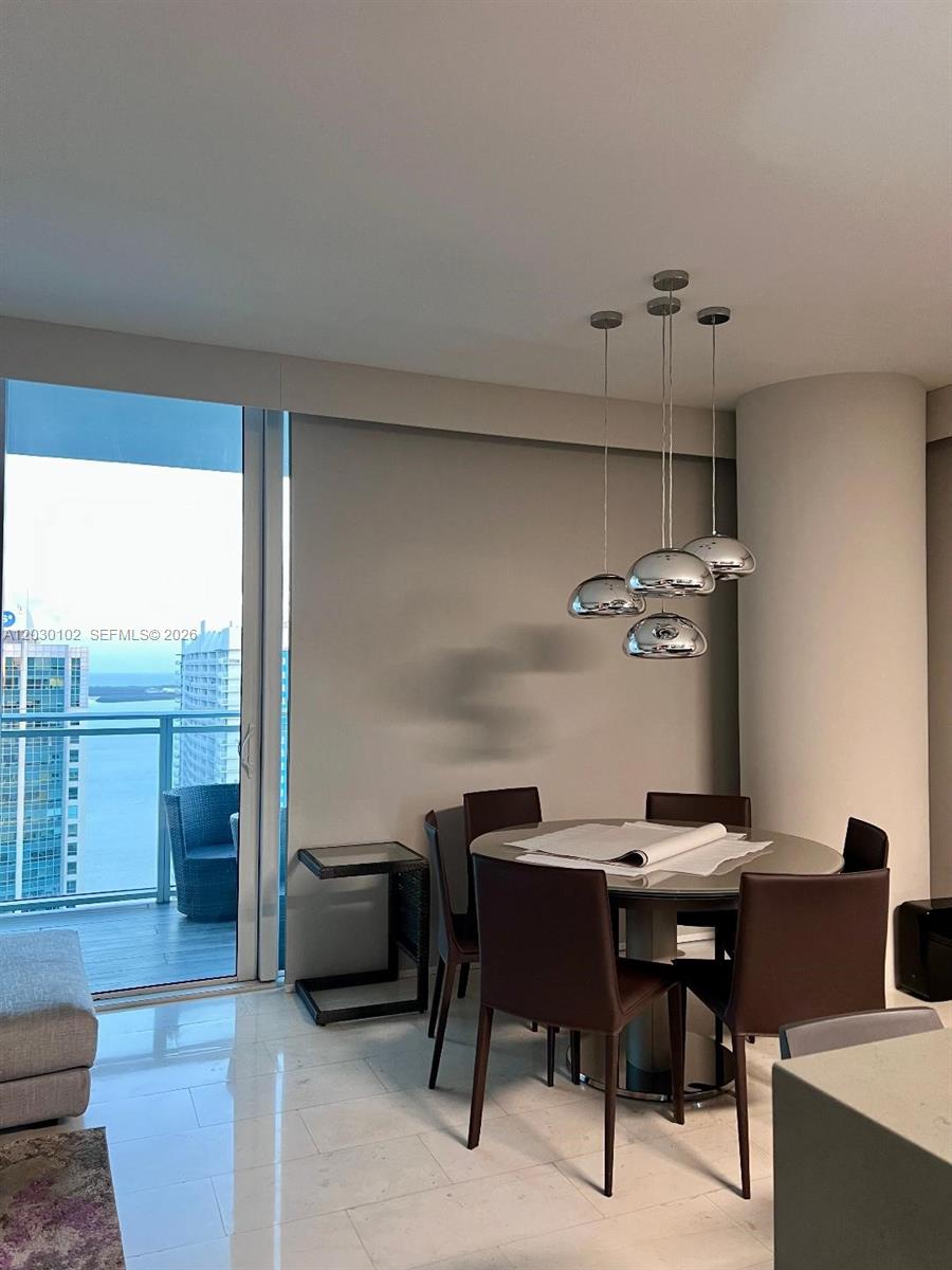 A dining area features a round glass table, brown chairs, and modern chrome pendant lights — 1080 Brickell Ave # 3600, Miami FL 33131, MIAMI, FL