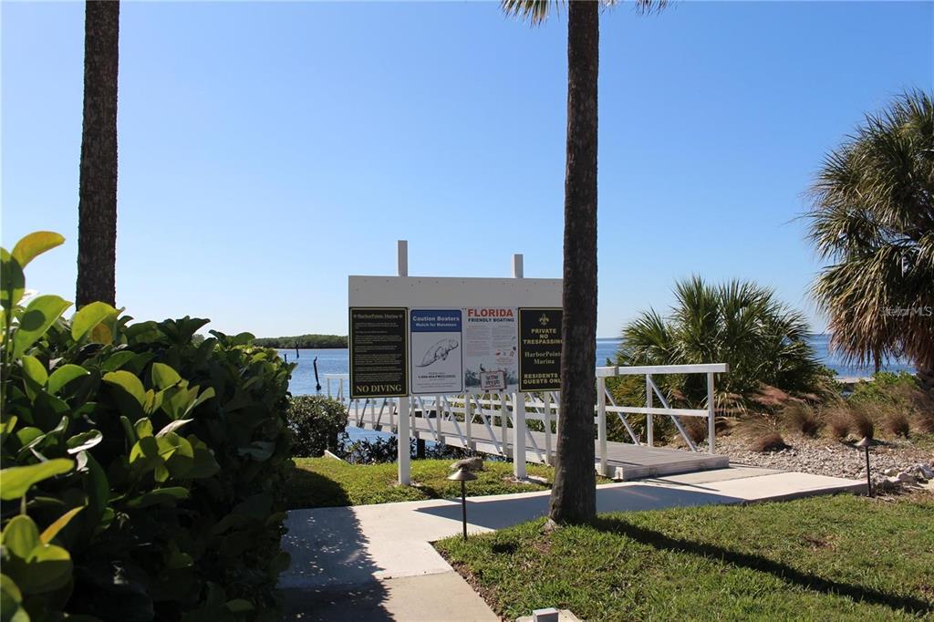 A wooden dock leads to the water behind a sign with boating and safety information — 4557 HARBORPOINTE DRIVE, PORT RICHEY, FL