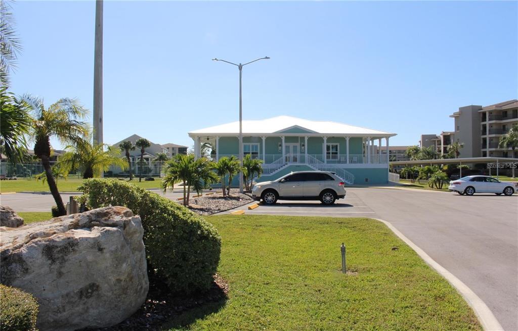 A light blue elevated building stands in a parking lot with palm trees and landscaping — 4557 HARBORPOINTE DRIVE, PORT RICHEY, FL
