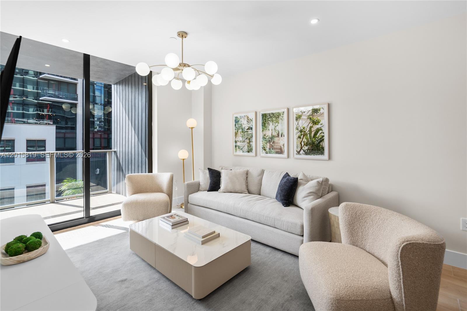 A modern living room features a beige sofa, two armchairs, a coffee table, and balcony views — 90 NE 32nd # 507, Miami FL 33137, MIAMI, FL