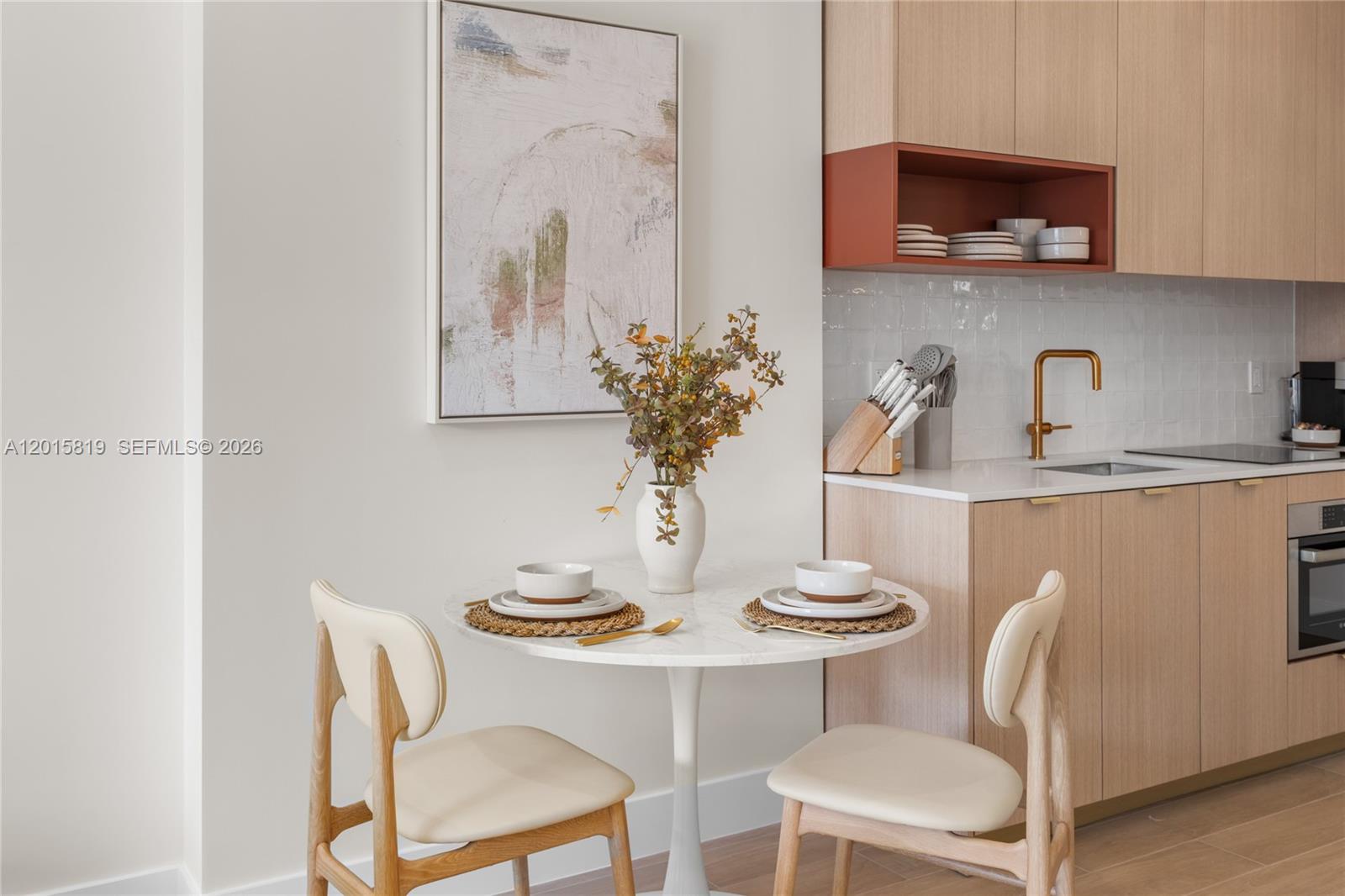 A small dining area features a round marble table, two chairs, and a modern kitchen — 90 NE 32nd # 507, Miami FL 33137, MIAMI, FL