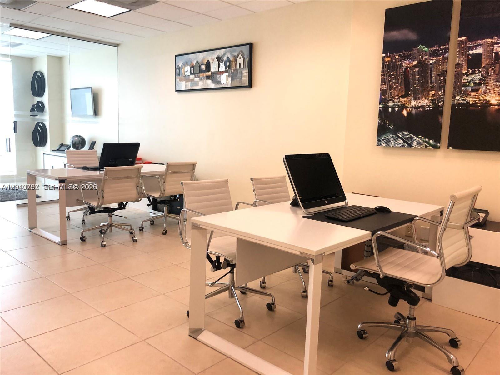 An office space features two white desks with computers and chairs on a tiled floor — 175 SW 7th St # 1805, Miami FL 33130, MIAMI, FL