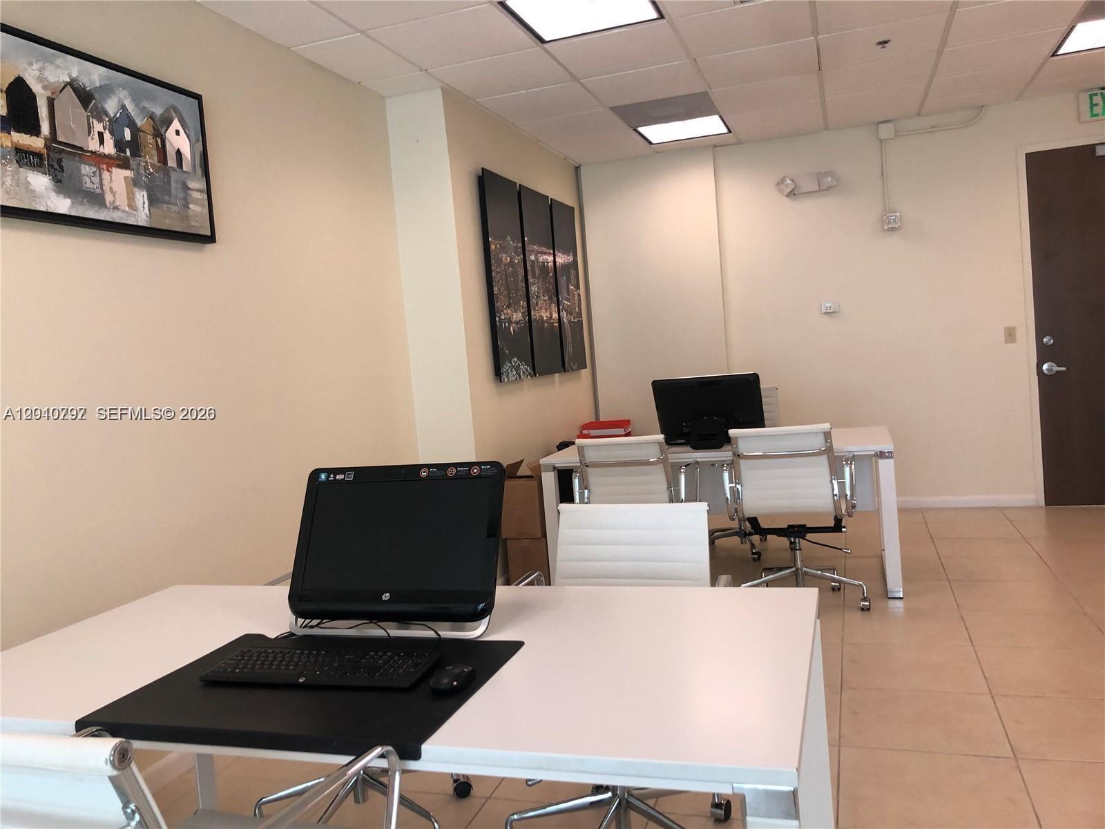 An office space features white desks, rolling chairs, and wall art on a beige wall — 175 SW 7th St # 1805, Miami FL 33130, MIAMI, FL