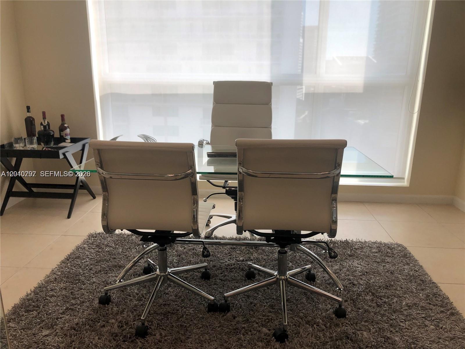 A home office features a glass desk, three white chairs, and a grey rug — 175 SW 7th St # 1805, Miami FL 33130, MIAMI, FL
