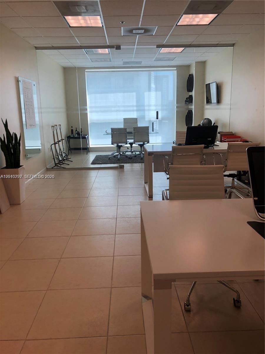 An office space features a glass-enclosed conference room, white desks, and tile flooring — 175 SW 7th St # 1805, Miami FL 33130, MIAMI, FL