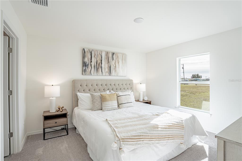 A bedroom features a tufted headboard, two nightstands with lamps, and a window with views — 18087 CLANTON AVENUE, PORT CHARLOTTE, FL