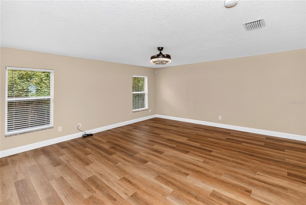An empty room with light-colored walls, wood-look flooring, two windows, and a ceiling fan — 690 W LISBON PARKWAY, DELAND, FL
