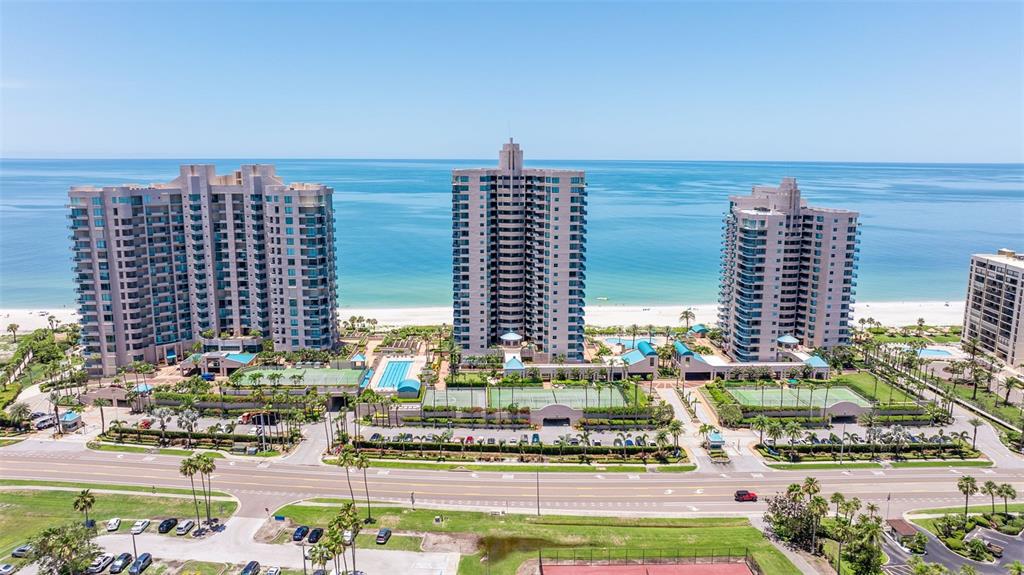 An aerial view of three high-rise residential buildings situated along a sandy beach — 1520 GULF BOULEVARD UNIT 1506, CLEARWATER BEACH, FL