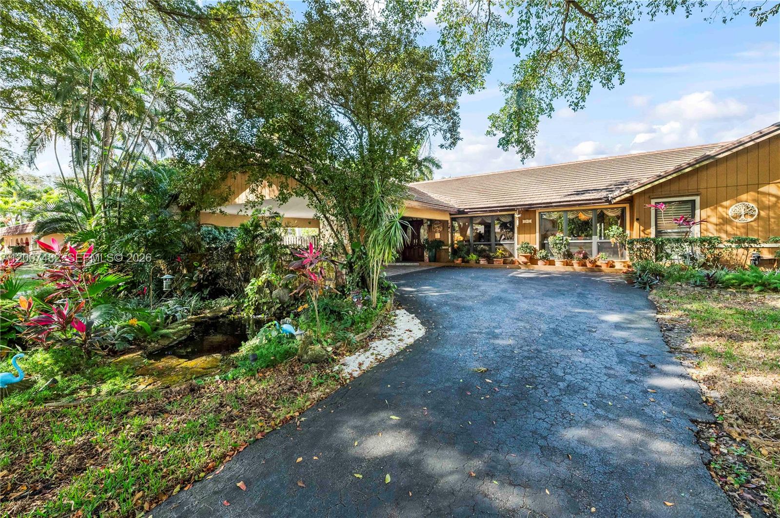 A single-story house with a brown exterior, a paved driveway, and a small garden pond — 10651 SW 27th St, Davie FL 33328, DAVIE, FL