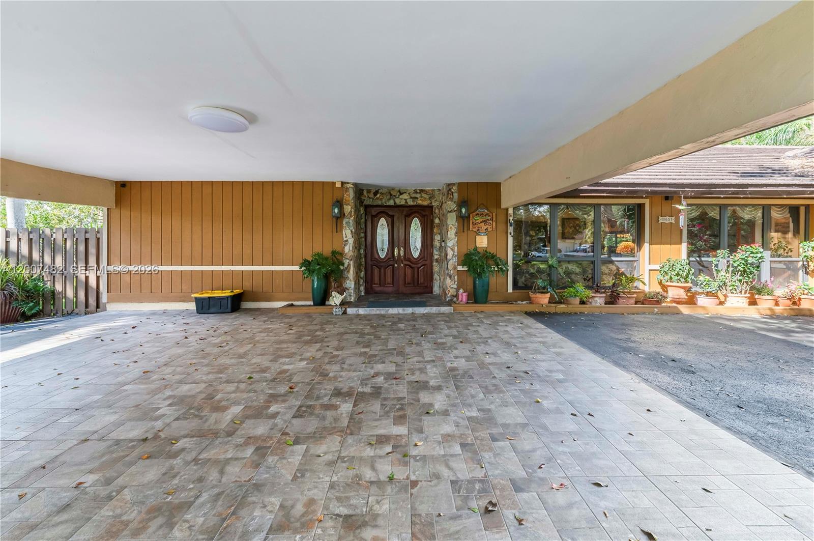 A covered entryway features a tiled driveway, wood-paneled walls, and double front doors — 10651 SW 27th St, Davie FL 33328, DAVIE, FL