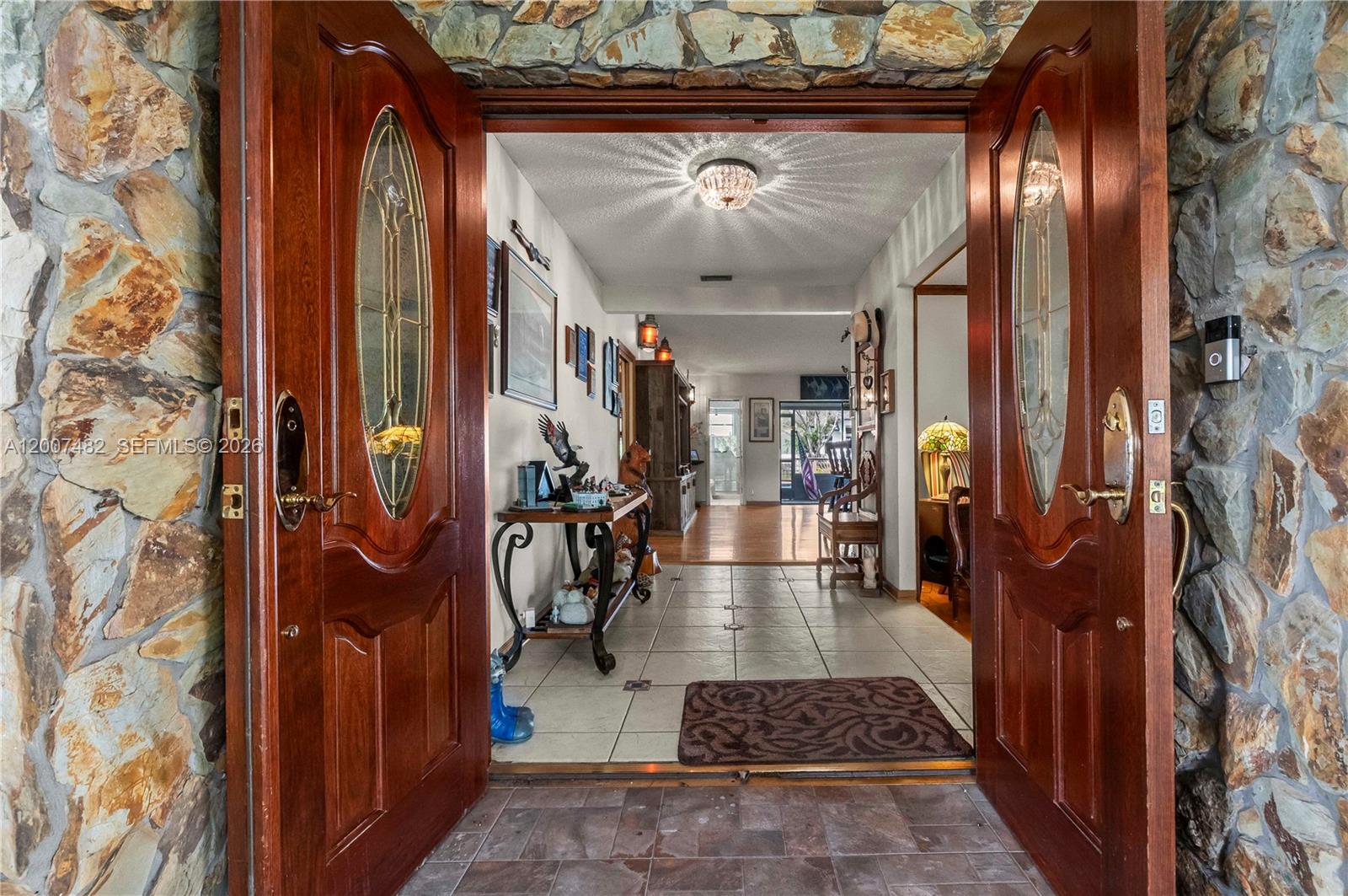A stone-walled entryway leads through double wooden doors into a tiled foyer and hallway — 10651 SW 27th St, Davie FL 33328, DAVIE, FL
