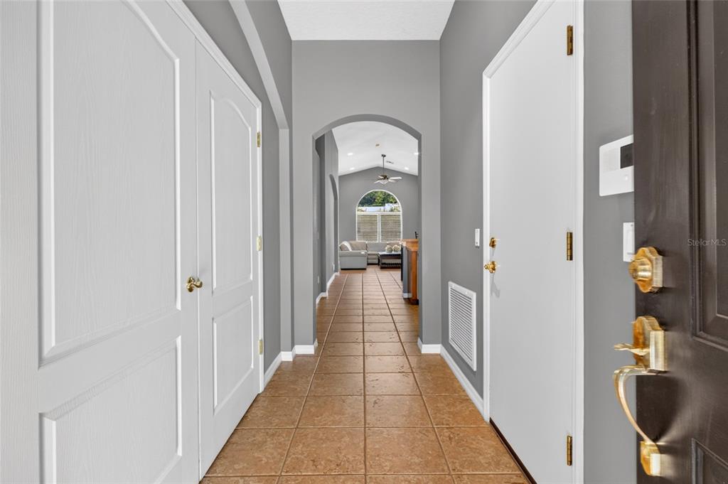 A tiled entryway leads through an arched hallway toward a living area with a window — 4618 CONROY CLUB DRIVE, ORLANDO, FL
