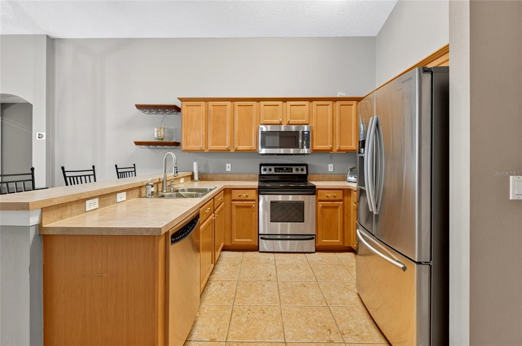 A kitchen features wood cabinets, stainless steel appliances, a breakfast bar, and tile flooring — 4618 CONROY CLUB DRIVE, ORLANDO, FL