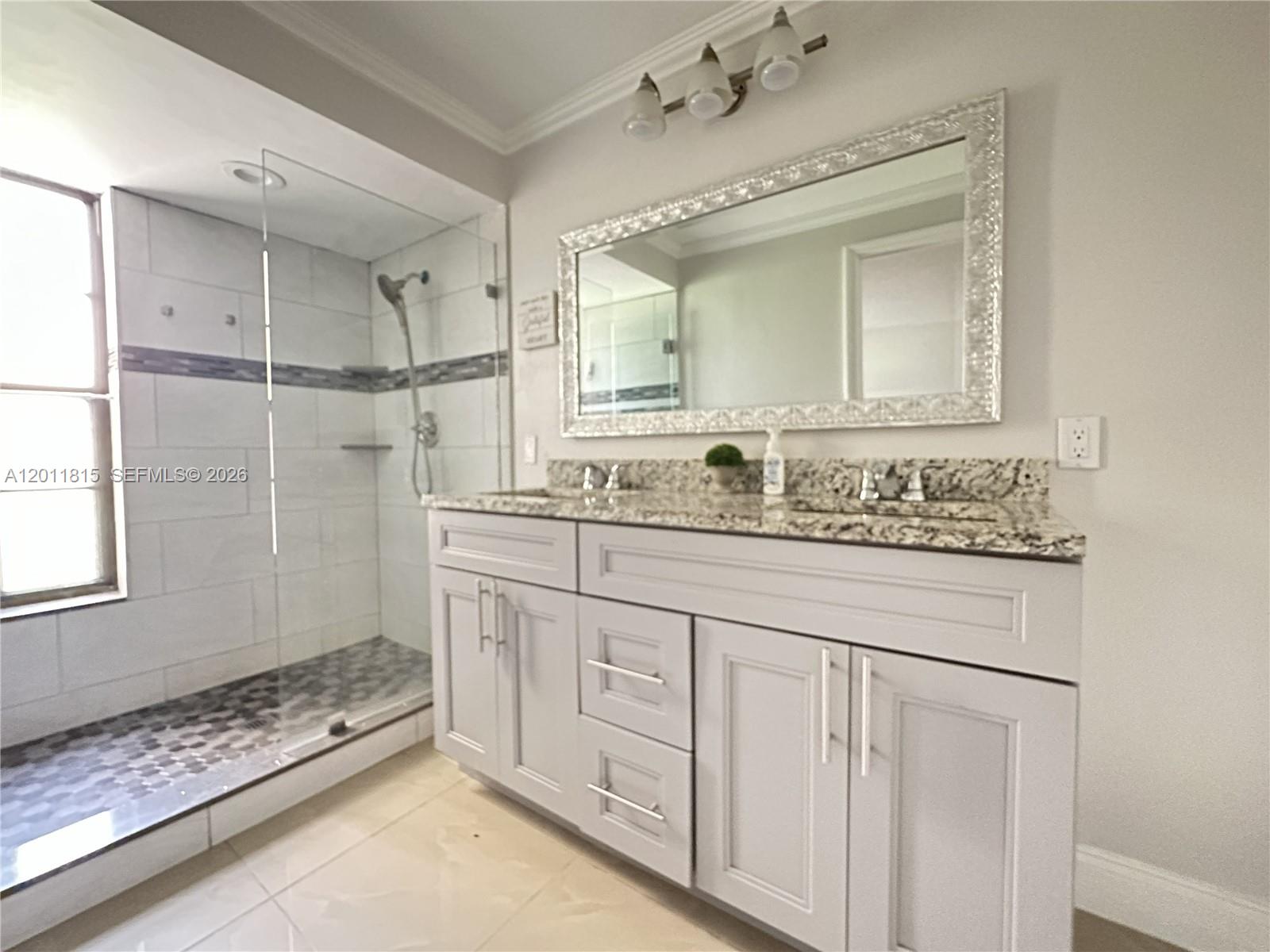 A bathroom features a double vanity with granite countertops, a large mirror, and a glass-enclosed shower — 9370 SW 8th St # 107, Boca Raton FL 33428, BOCA RATON, FL