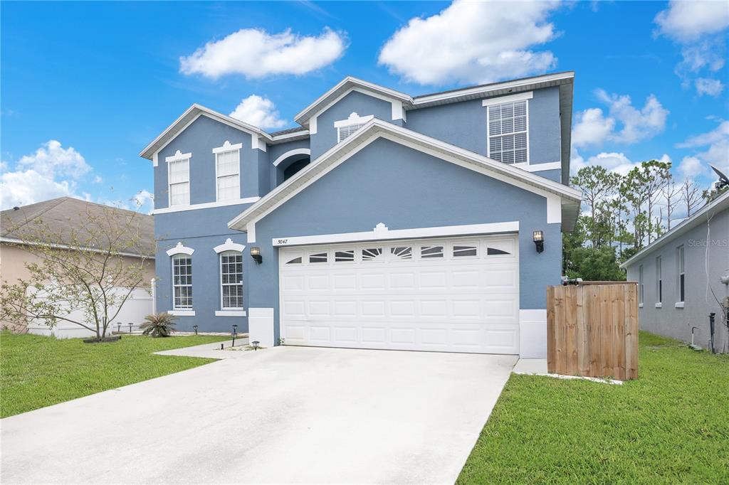 A two-story blue house with a white garage door and a concrete driveway — 5047 ADAIR OAK DRIVE, ORLANDO, FL