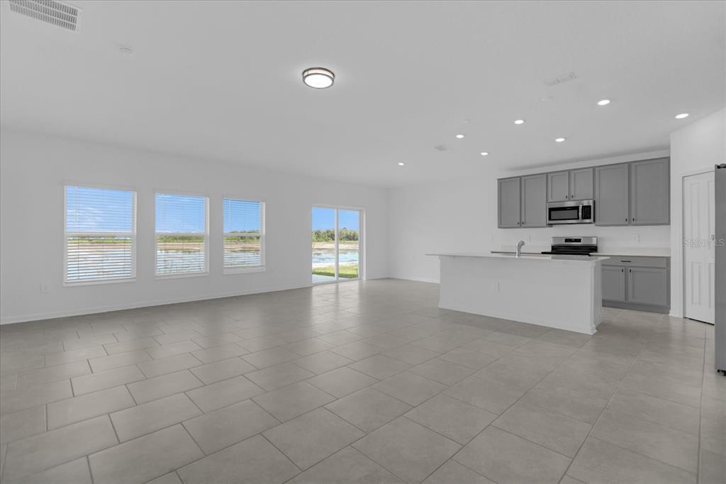 An open-concept kitchen and living area with gray cabinets, a white island, and tile flooring — 4939 WORCHESTER DRIVE, KISSIMMEE, FL
