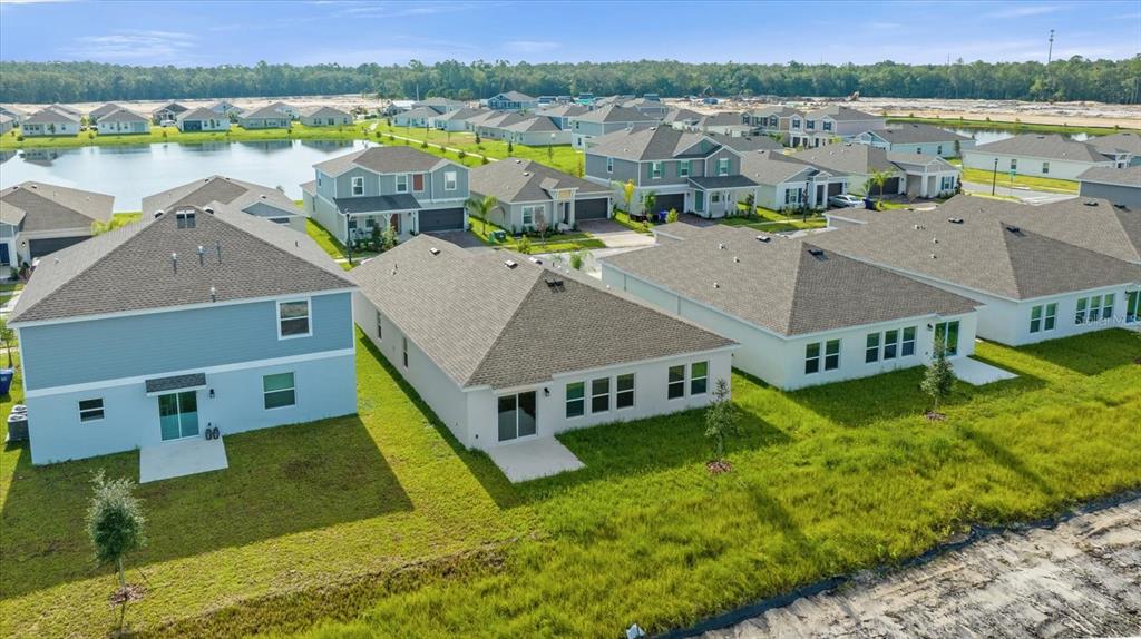 An aerial view shows several suburban houses with gray roofs and backyards near a pond — 4939 WORCHESTER DRIVE, KISSIMMEE, FL