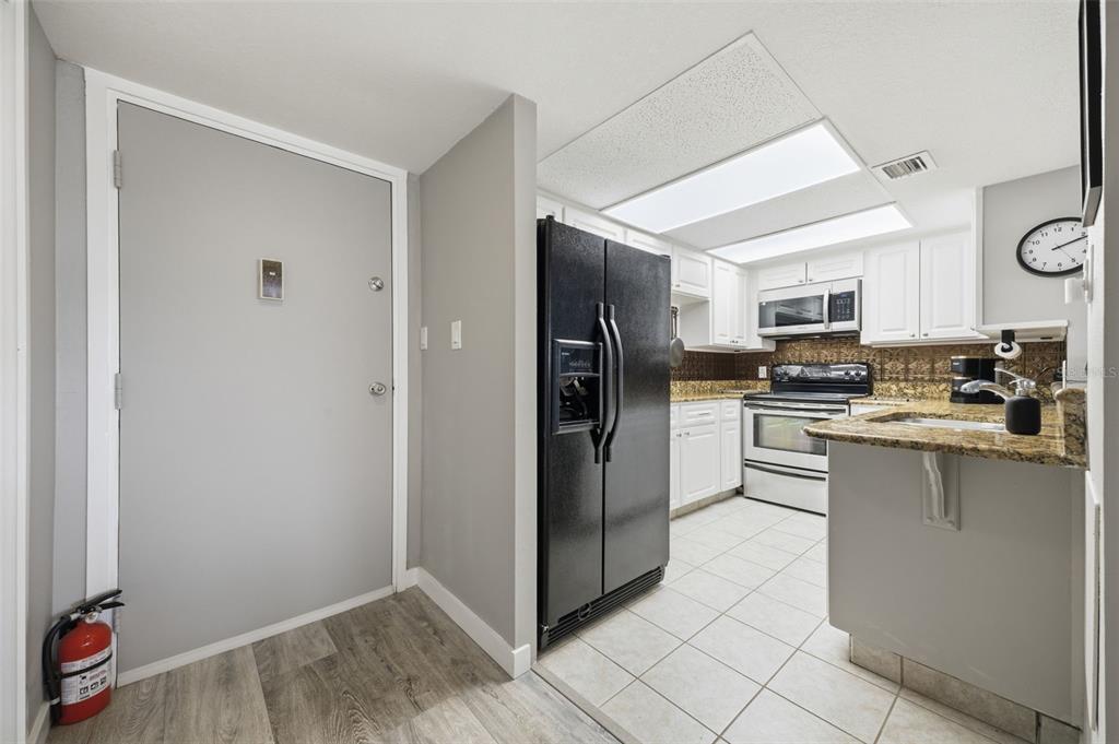 A kitchen features white cabinets, granite countertops, a black refrigerator, and a tile floor — 4141 BAYSHORE BOULEVARD UNIT 606, TAMPA, FL