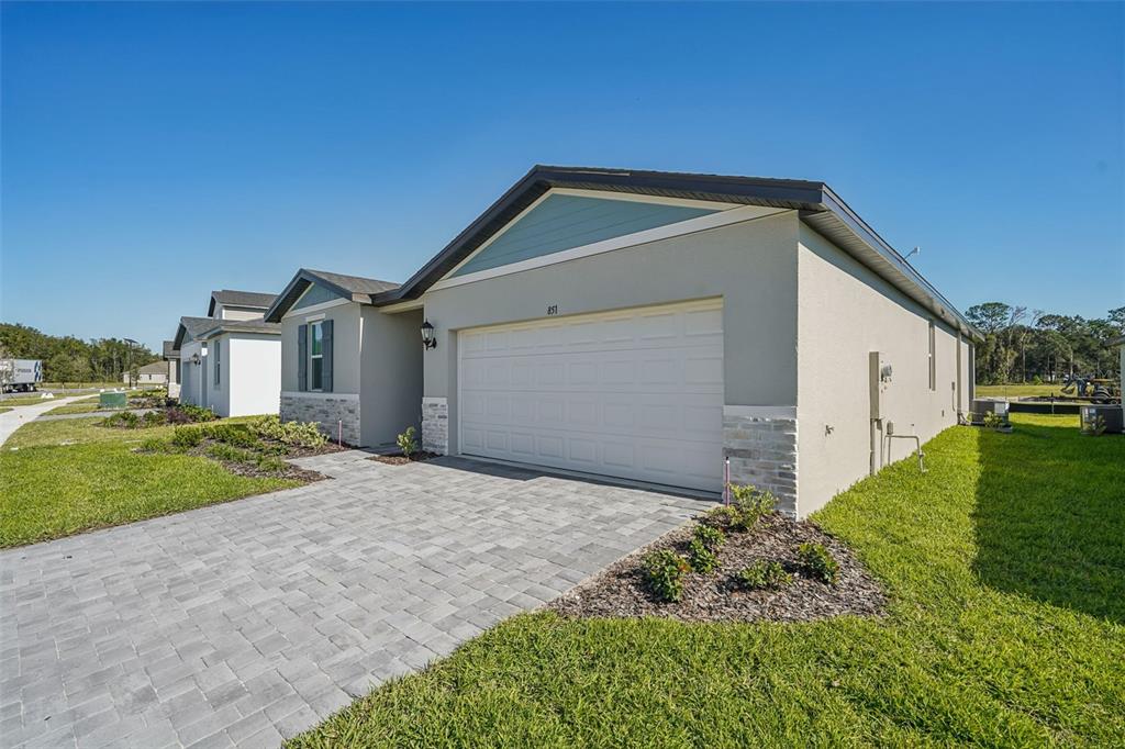 A single-story house with a white garage door, stone accents, and a paved driveway — 851 SUNSHOWER DRIVE, LADY LAKE, FL