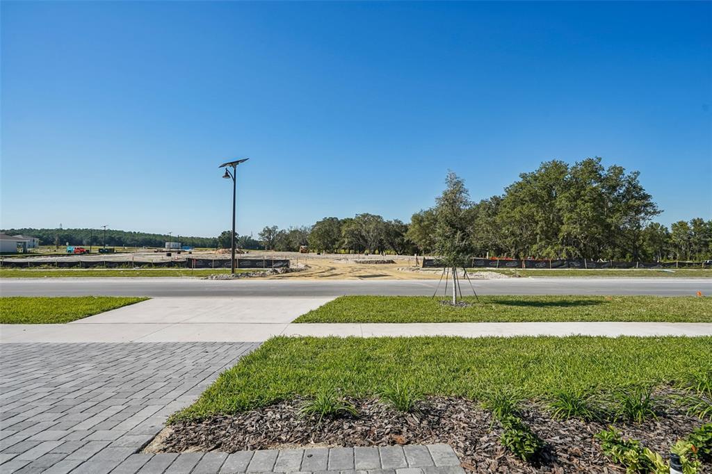 A view from a paved driveway looking across a street toward a cleared construction site — 851 SUNSHOWER DRIVE, LADY LAKE, FL