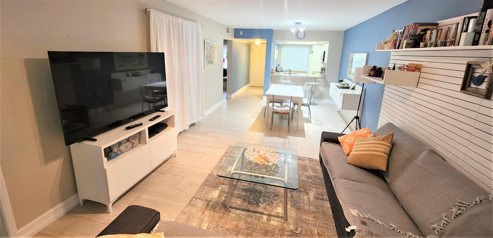 A living room with a television, sofa, coffee table, and an adjacent dining area — 600 Egret Circle # 7201, Delray Beach FL 33444, DELRAY BEACH, FL