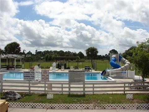 An outdoor swimming pool with a blue water slide and a white fence — 470 N Cabbage Palm St, Clewiston FL 33440, CLEWISTON, FL
