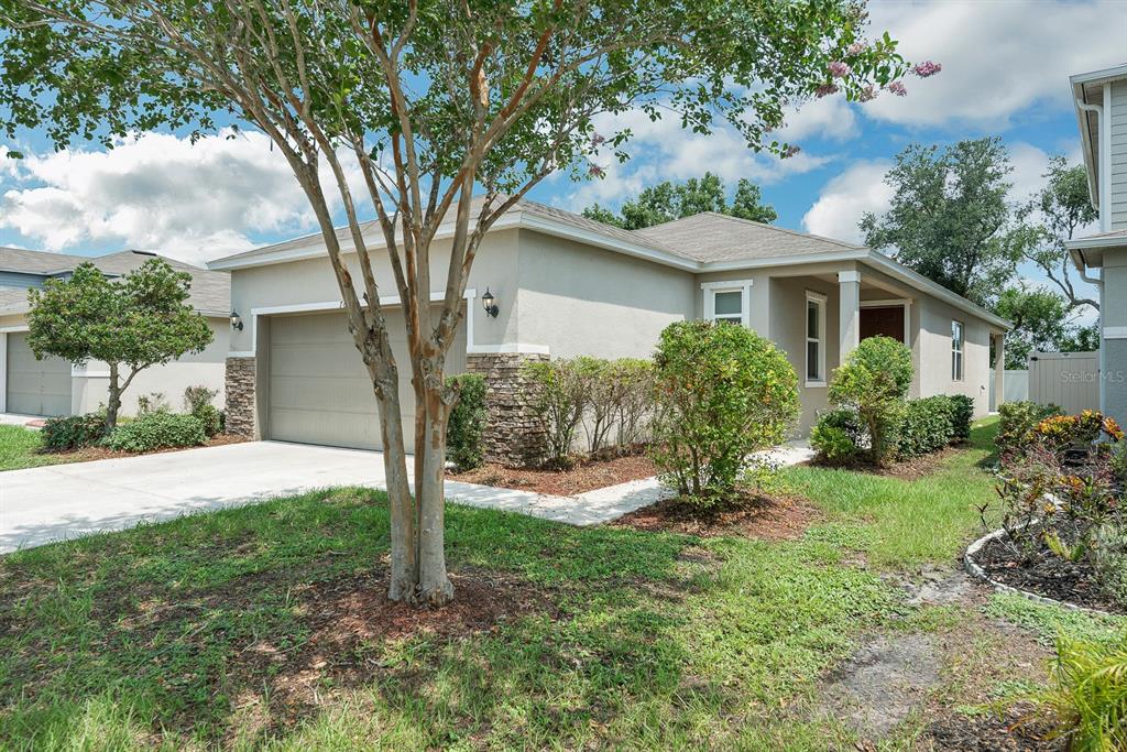 A single-story house with a beige stucco exterior, stone accents, and a two-car garage — 7608 SUNSHINE BRIDGE AVENUE, GIBSONTON, FL
