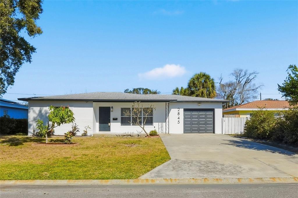A single-story white house with a dark garage door and a concrete driveway — 2845 64TH TERRACE S, ST PETERSBURG, FL