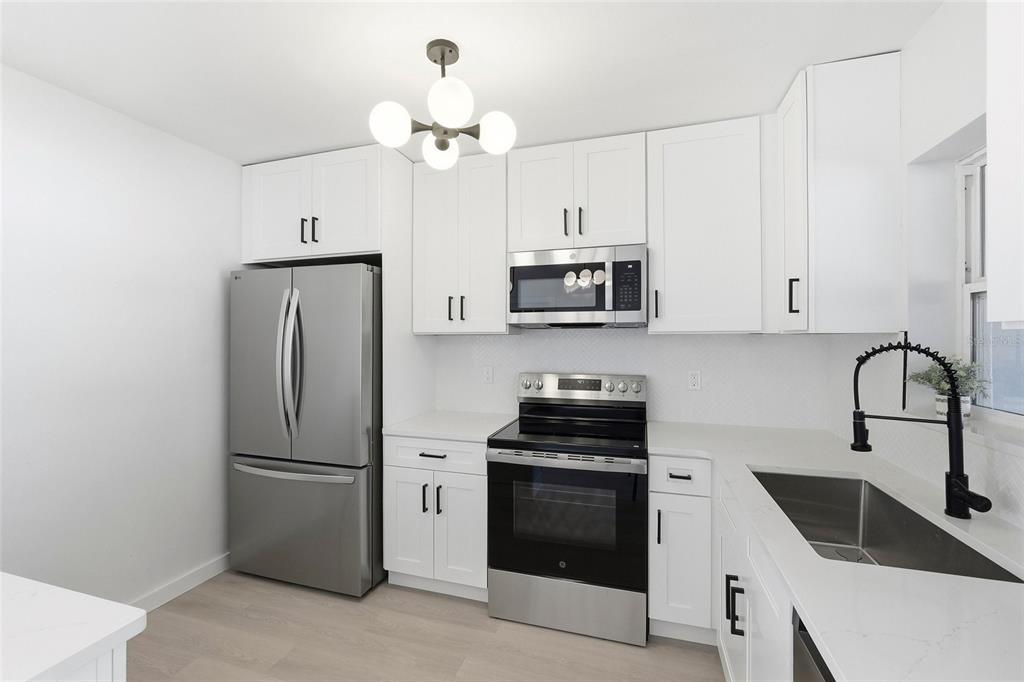 A modern kitchen features white cabinets, stainless steel appliances, and a black faucet — 2845 64TH TERRACE S, ST PETERSBURG, FL