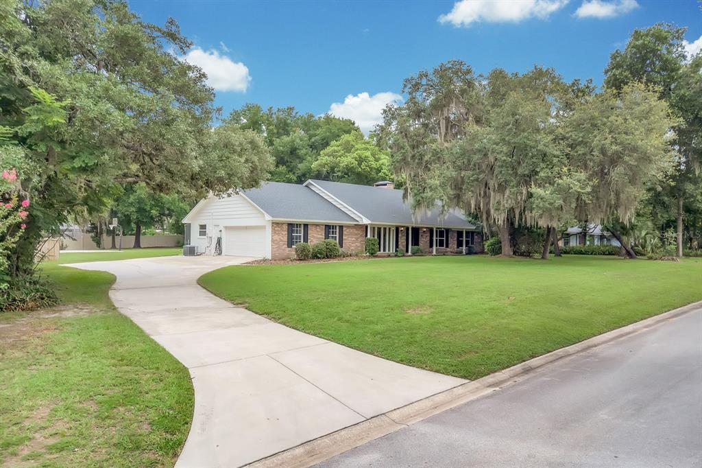 A single-story brick house with a white garage and a large front lawn — 112 FOREST PARK COURT, LONGWOOD, FL