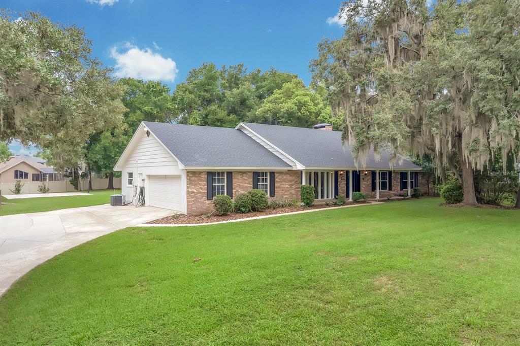 A single-story brick house with a white garage and a large front lawn — 112 FOREST PARK COURT, LONGWOOD, FL