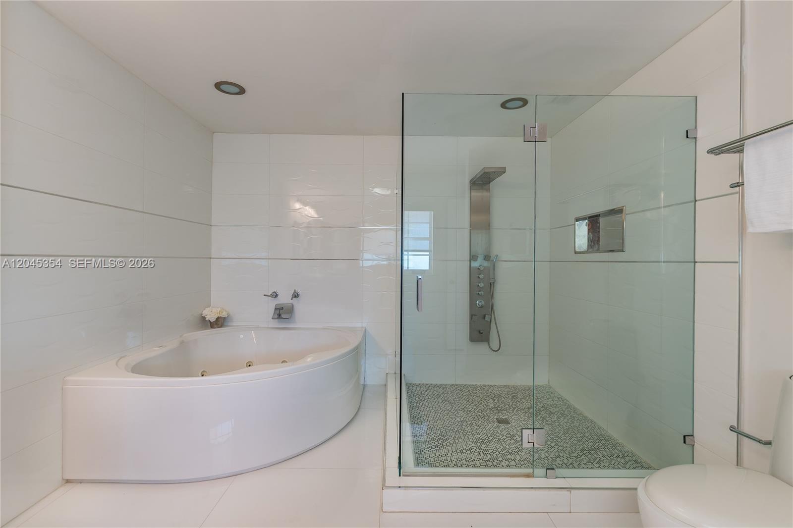 A modern bathroom features a corner soaking tub, a glass-enclosed shower, and white tile — 5132 NW 106th Ave # 5132, Doral FL 33178, DORAL, FL