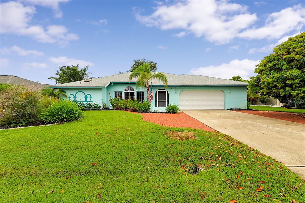 A light blue single-story house features a white garage door, a palm tree, and landscaping — 339 BARCELONA STREET, PUNTA GORDA, FL