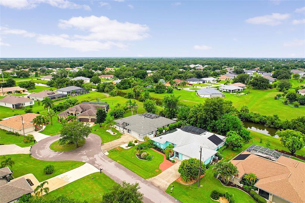 An aerial view of a suburban neighborhood with houses, green lawns, and a small canal — 339 BARCELONA STREET, PUNTA GORDA, FL