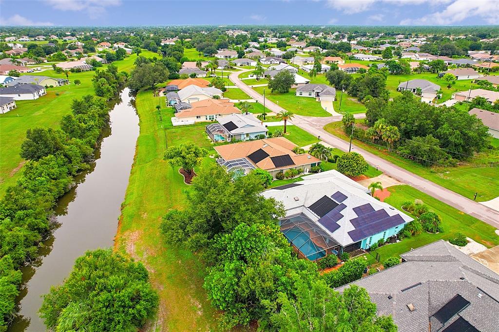 An aerial view shows a suburban neighborhood with houses, swimming pools, and a winding canal — 339 BARCELONA STREET, PUNTA GORDA, FL