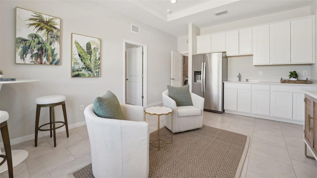 A kitchen area with white cabinets, stainless steel appliances, and a small seating arrangement — 1025 CHASEHILL LANE, ZEPHYRHILLS, FL