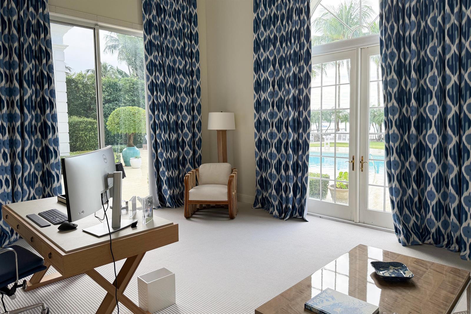 A home office features a wooden desk, patterned blue curtains, and views of a swimming pool — 1494 N Lake Way, Palm Beach FL 33480, PALM BEACH, FL