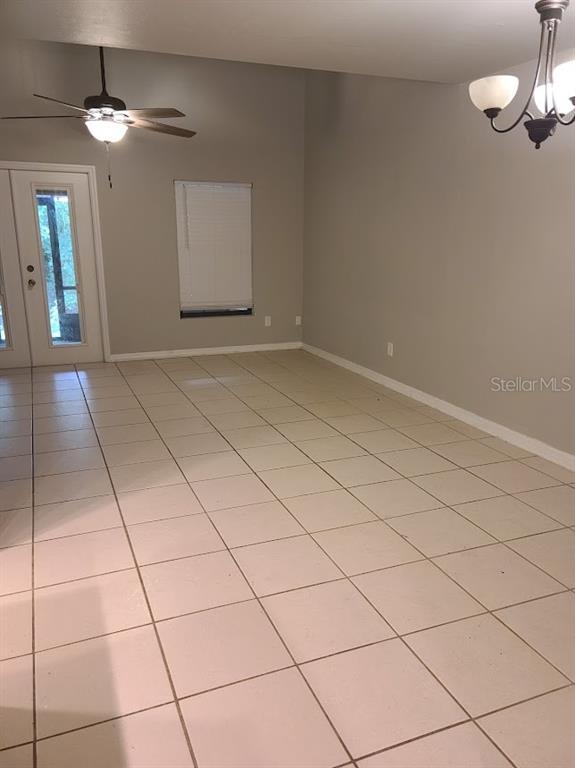A room with light-colored tile flooring, a ceiling fan, and a glass-paneled door — 900 SW 62ND BOULEVARD UNIT B 8, GAINESVILLE, FL