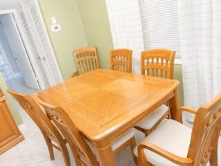 A wooden dining table with four chairs is positioned in a room with light green walls — 175 Flanders D, Delray Beach FL 33484, DELRAY BEACH, FL