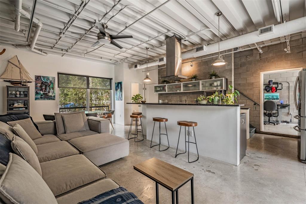 An open-concept living room and kitchen with concrete floors, exposed ceiling pipes, and bar seating — 3107 W DE LEON STREET UNIT 6, TAMPA, FL