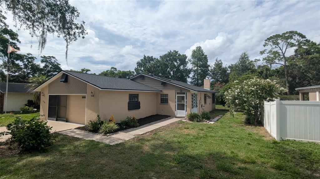 A single-story house with a tan stucco exterior, a dark shingled roof, and a garage — 104 QUAIL RIDGE COURT, SANFORD, FL