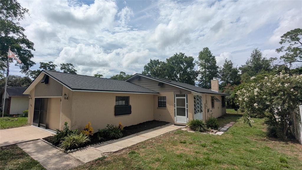 A single-story house with a tan stucco exterior, a dark shingled roof, and a garage — 104 QUAIL RIDGE COURT, SANFORD, FL