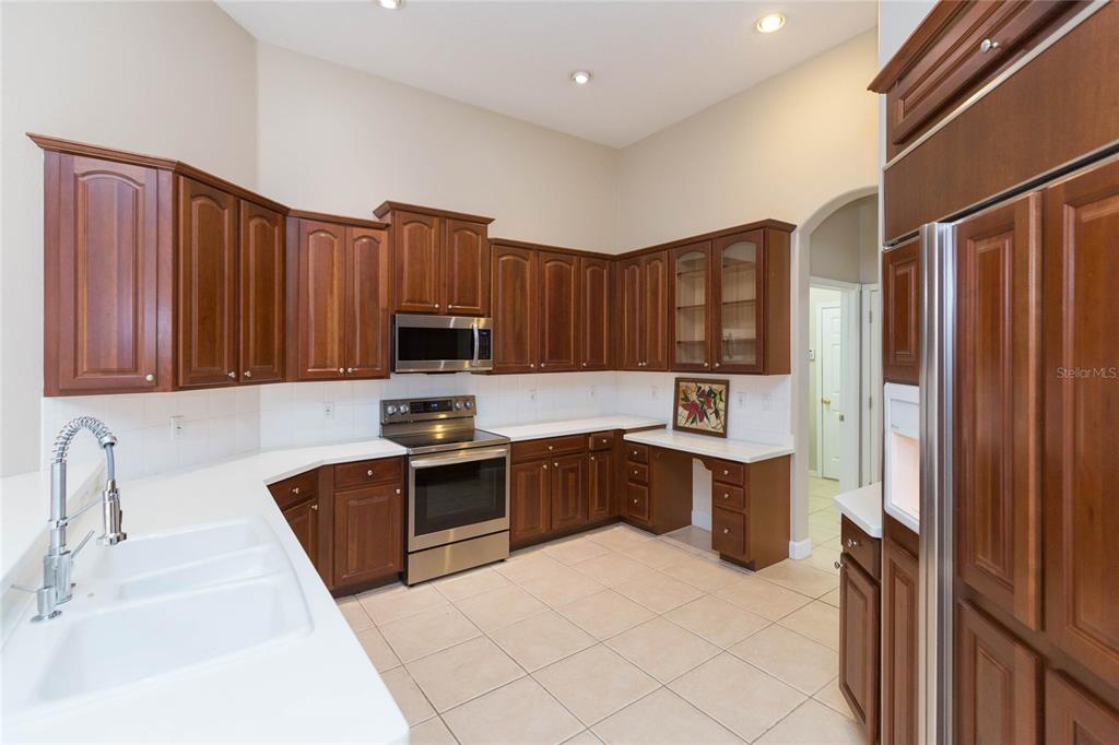A kitchen with wood cabinets, stainless steel appliances, and white countertops on tile flooring — 4813 ARTESIAN ROAD, LAND O LAKES, FL