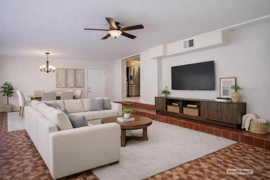 A living room with a sunken seating area, tile flooring, and a wall-mounted television — 4621 JOHN MOORE ROAD, BRANDON, FL