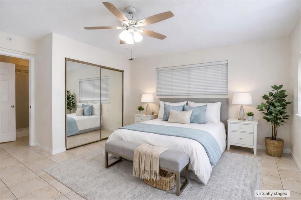 A bedroom with a queen bed, mirrored closet doors, a ceiling fan, and light-colored flooring — 4621 JOHN MOORE ROAD, BRANDON, FL