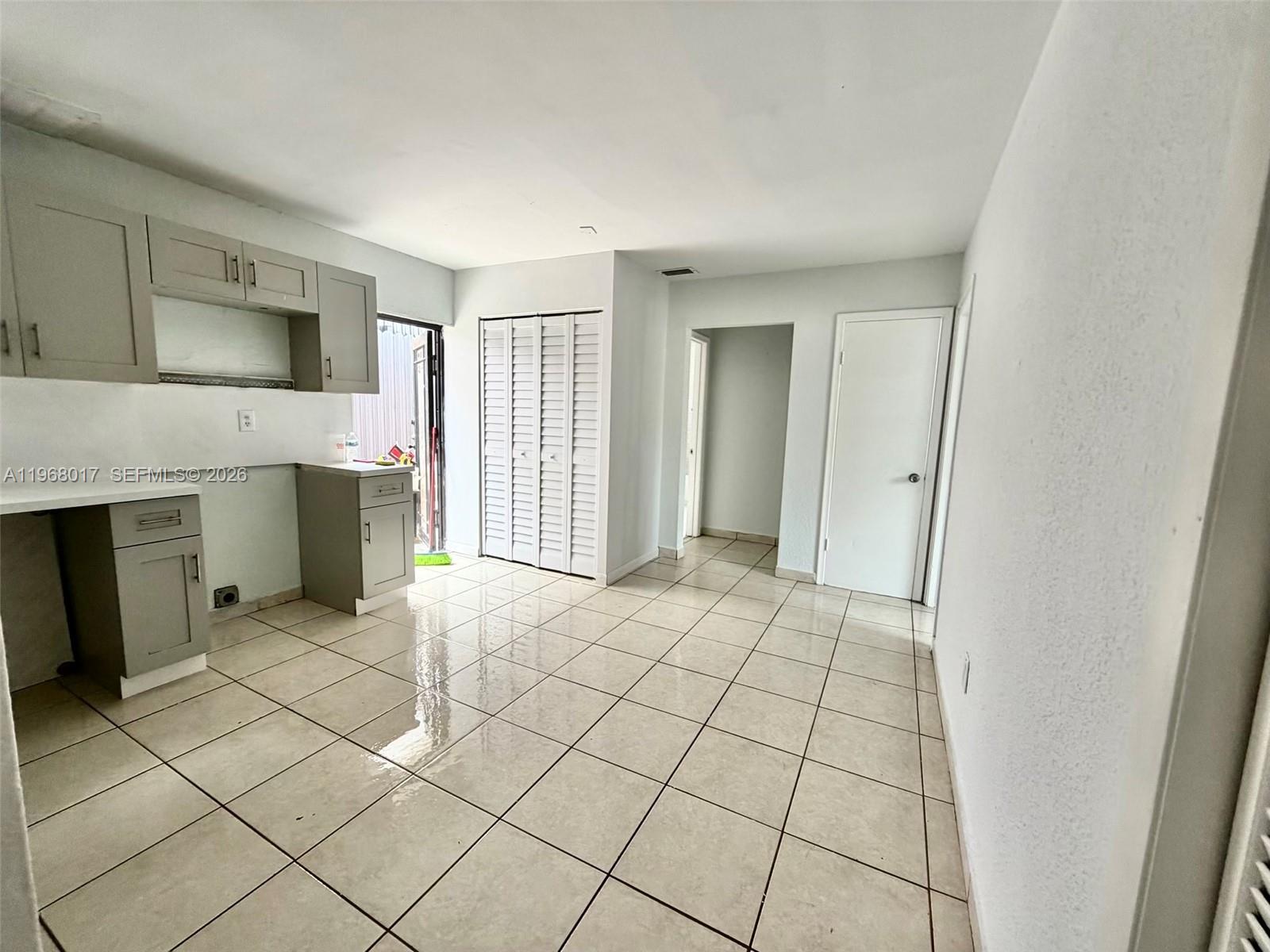 A kitchen with gray cabinets and tiled floors leads to an exterior door — 137xx SW 32nd St, Miami FL 33175, MIAMI, FL