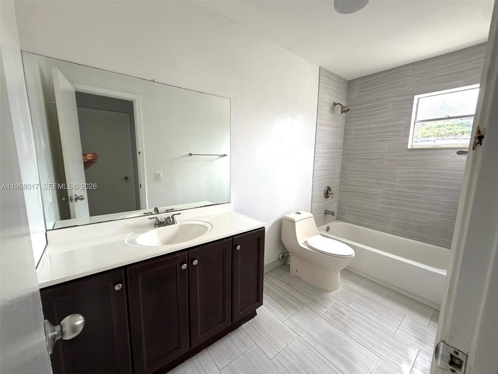 A bathroom features a dark wood vanity, a large mirror, and a tiled tub-shower combo — 137xx SW 32nd St, Miami FL 33175, MIAMI, FL
