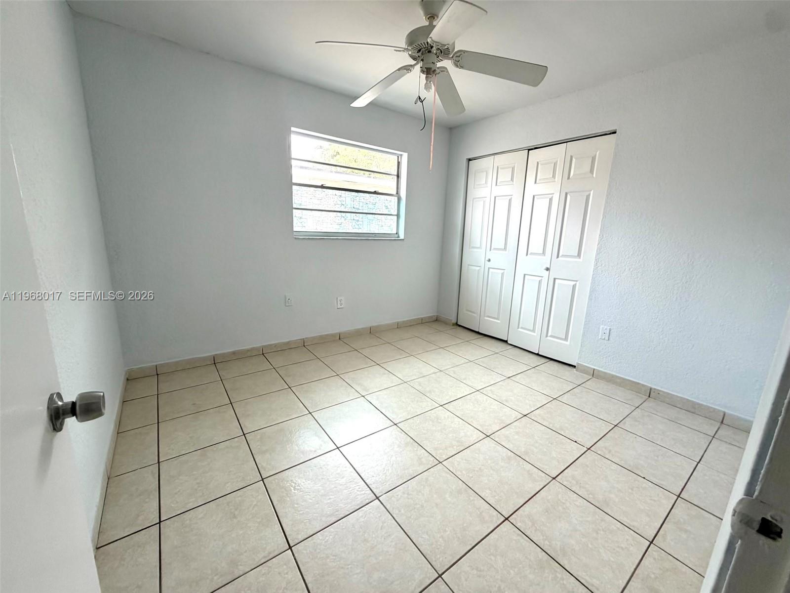 A bedroom features light-colored walls, tiled flooring, a ceiling fan, and a white closet — 137xx SW 32nd St, Miami FL 33175, MIAMI, FL