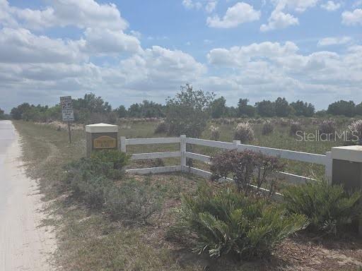A white fence marks the entrance to a large, grassy, undeveloped lot — 0 0 ARTIFACT DRIVE, ZEPHYRHILLS, FL